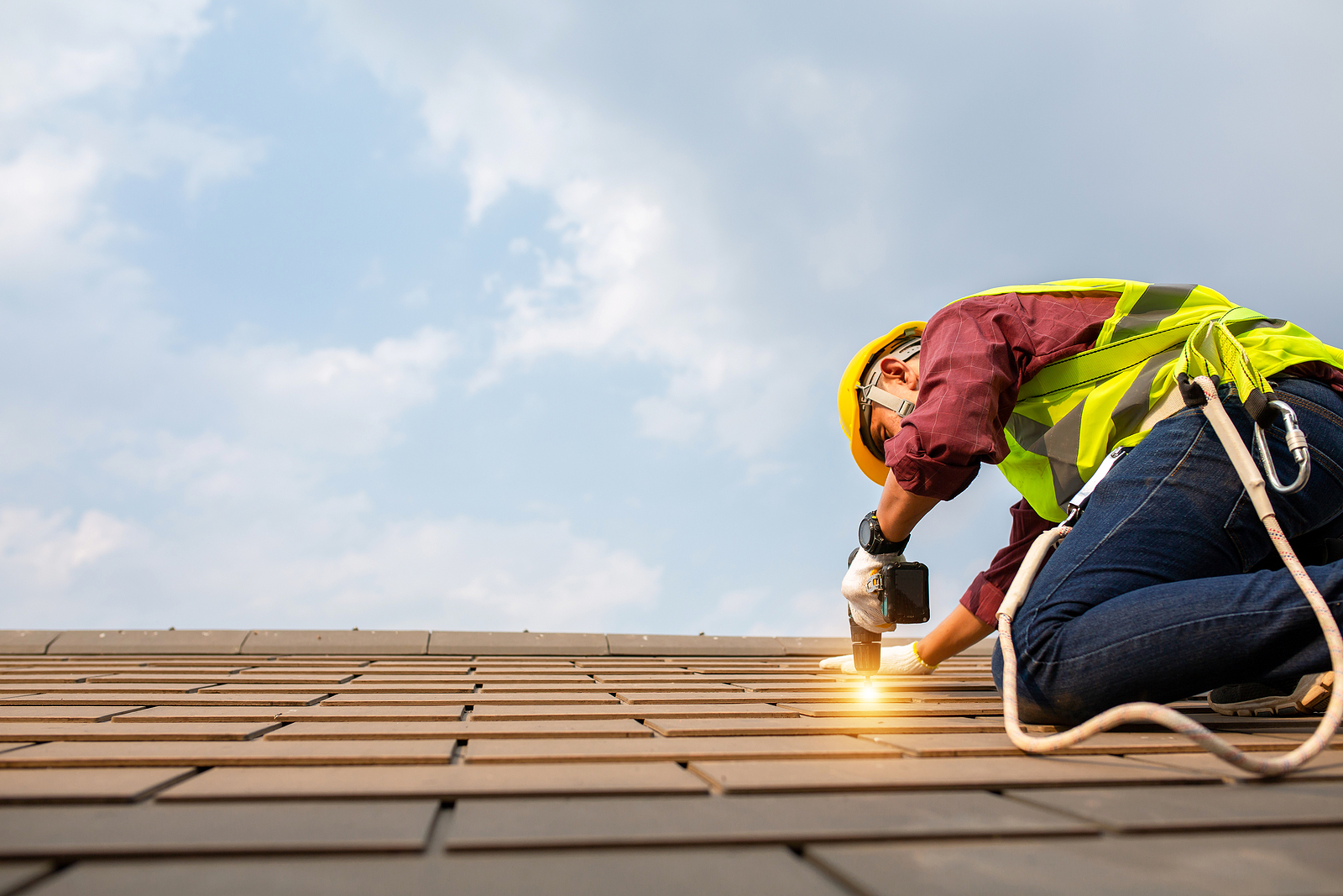 Construction worker installing a roof replacement. Learn more about the pros and cons of a roof replacement vs reroof in this article.